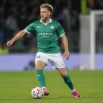 Een Lommelse speler dribbelt met de bal tijdens een bekerwedstrijd.
