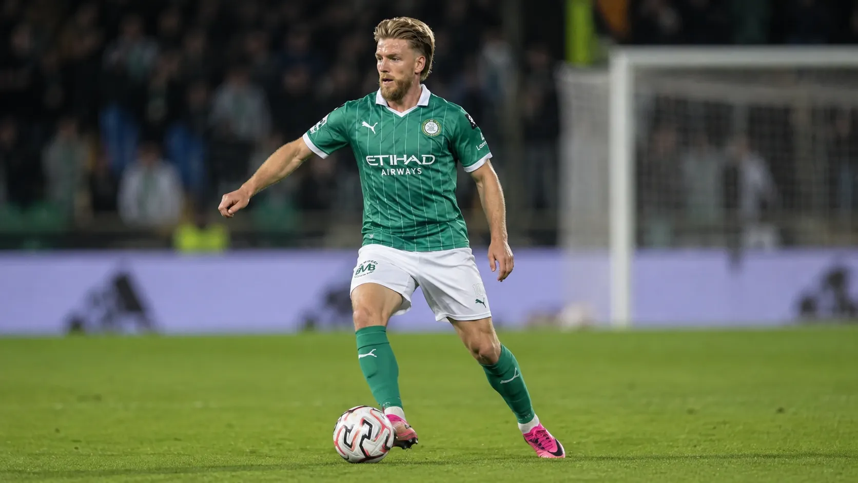 Een Lommelse speler dribbelt met de bal tijdens een bekerwedstrijd.