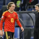 Belgische international in rood nationaal tenue wandelt na de wedstrijd langs de zijlijn.