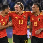 Drie Belgische internationals vieren samen op het veld.