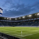Een leeg voetbalstadion met een Israëlische vlag aan een vaste vlaggenmast naast het veld.