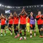 Een groep Belgische internationals applaudisseert samen op het veld in een stadion.
