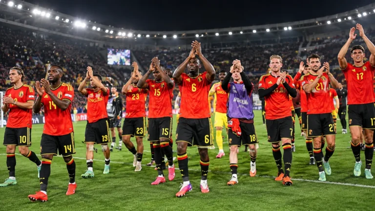 Een groep Belgische internationals applaudisseert samen op het veld in een stadion.
