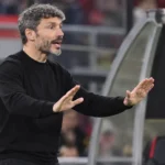 Mark van Bommel geeft aanwijzingen naast het veld, met een subtiel embleem van de Rode Duivels op de dug-out.