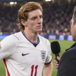 Anthony Gordon in het witte shirt van Engeland tijdens een interview langs het veld.