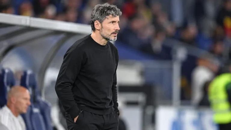 Mark van Bommel in zwarte kleding langs de zijlijn bij een wedstrijd van België.