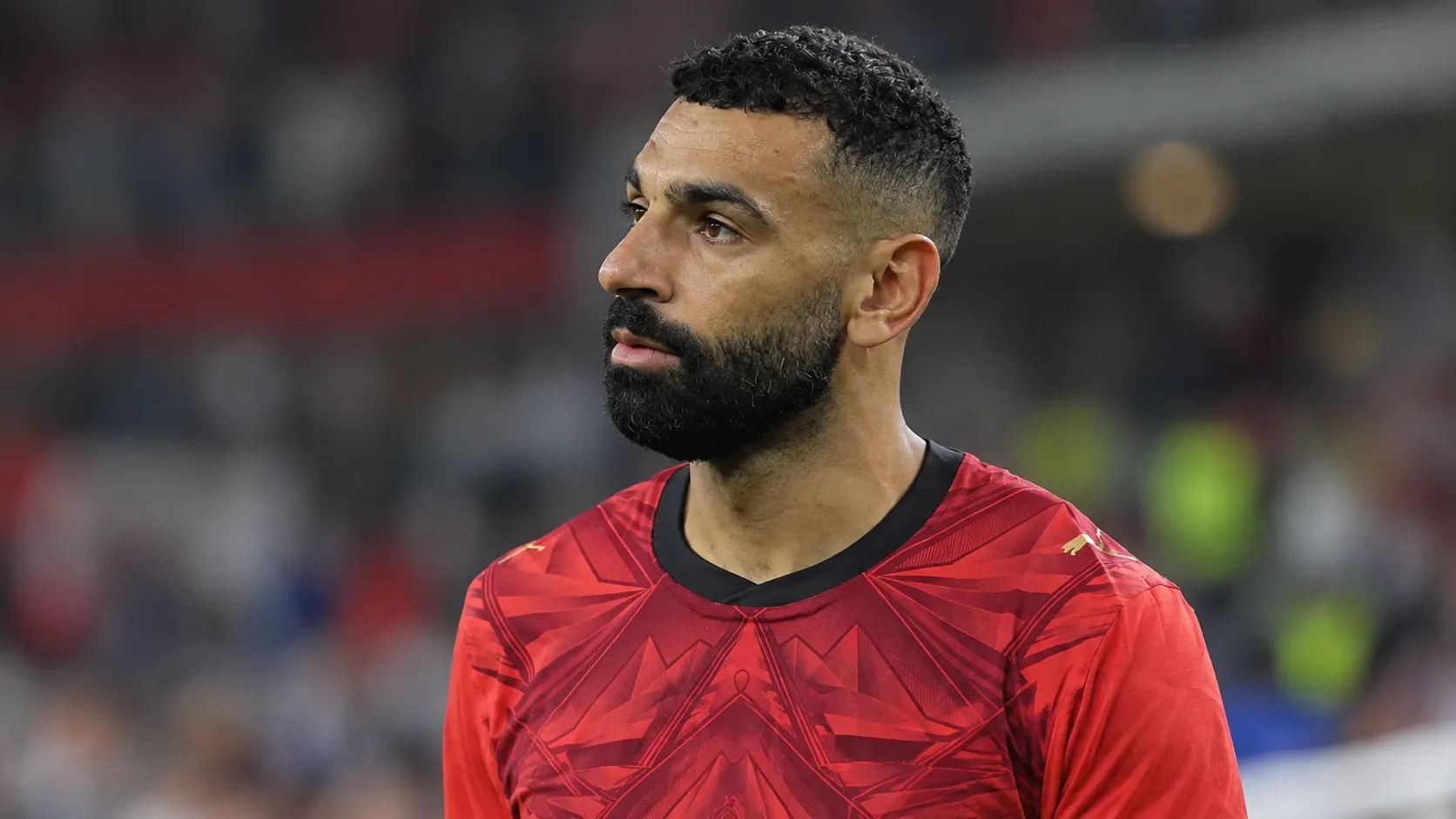 Mohamed Salah in het rode shirt van Egypte in een stadionomgeving.