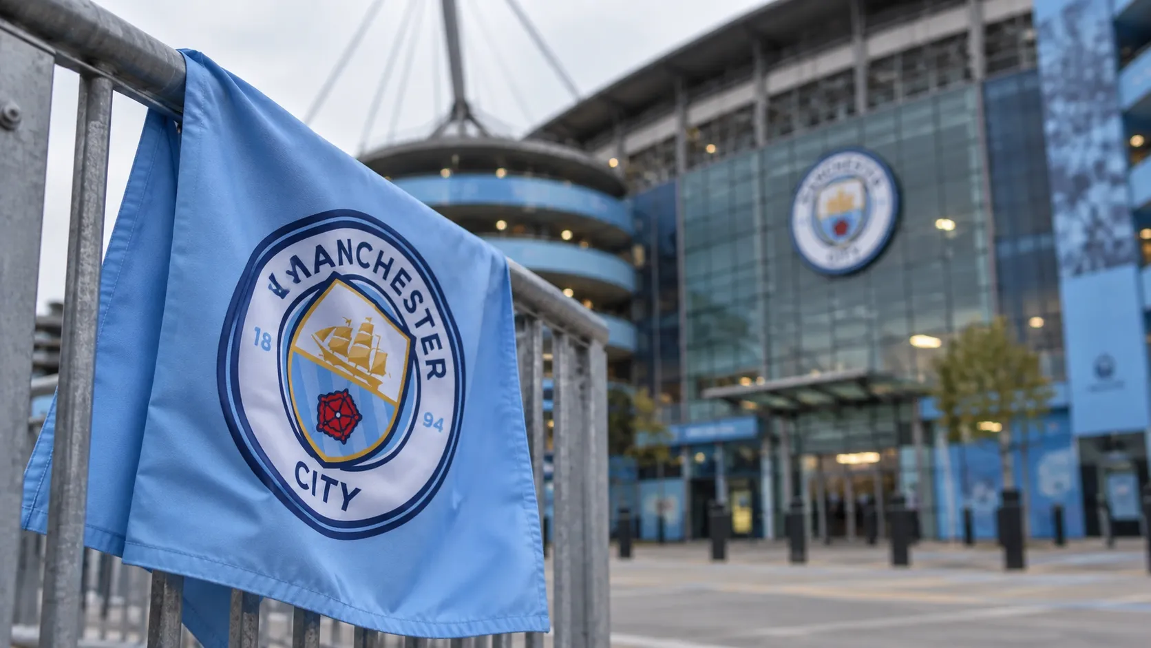 Een lichtblauwe vlag van Manchester City aan een stadioningang.