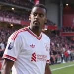 Alexander Isak in een wit Liverpool-shirt aan de rand van het veld.