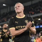 Erling Haaland applaudisseert in het zwartgele tenue van Manchester City in een verlicht stadion.