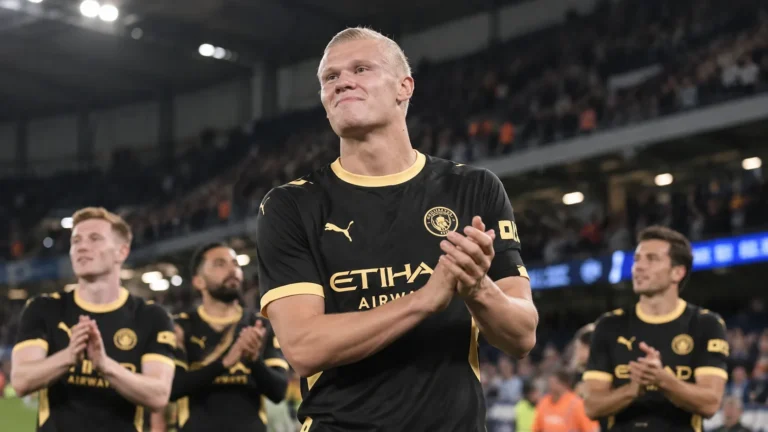 Erling Haaland applaudisseert in het zwartgele tenue van Manchester City in een verlicht stadion.