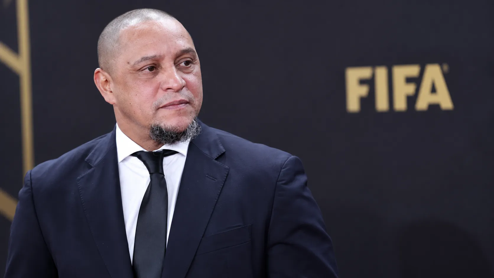 Roberto Carlos in donker pak tijdens een formeel FIFA-voetbalevenement.