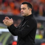 Xavi Hernández applaudisseert als bondscoach langs de zijlijn van een voetbalstadion.