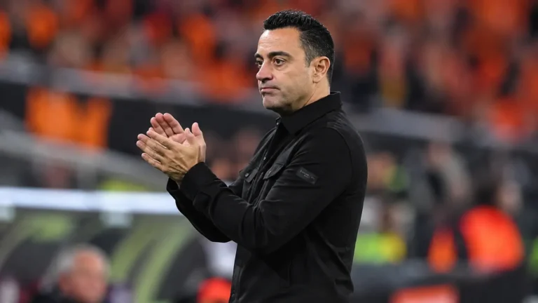 Xavi Hernández applaudisseert als bondscoach langs de zijlijn van een voetbalstadion.