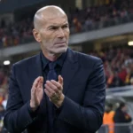 Zinedine Zidane applaudisseert langs de zijlijn van een stadion.