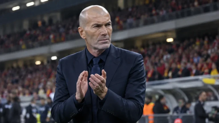 Zinedine Zidane applaudisseert langs de zijlijn van een stadion.