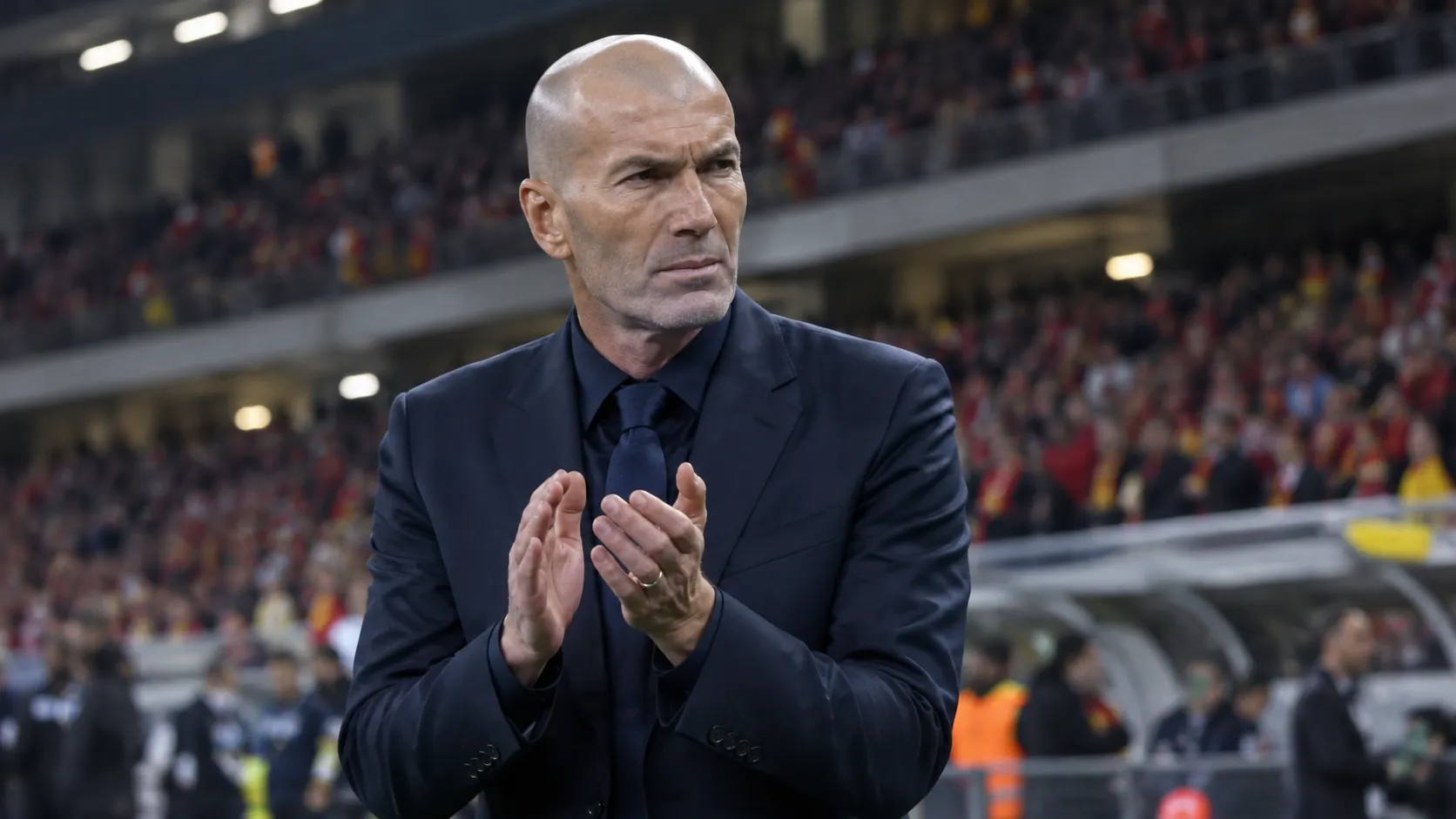 Zinedine Zidane applaudisseert langs de zijlijn van een stadion.