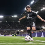 Lukas Ambros trapt een bal tijdens een wedstrijd van RSC Anderlecht onder de stadionlichten.