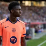 Jesse Bisiwu in het oranje shirt van FC Barcelona bij een wedstrijdmoment langs de zijlijn.