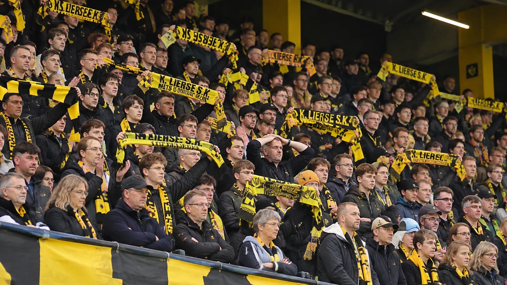 Lierse-supporters met geel-zwarte sjaals in de tribune.