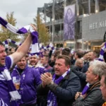Een groep supporters met paars-witte sjaals op een stadionplein.