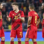 Vier Belgische spelers in rode nationale ploegtenues tijdens een wedstrijdonderbreking.