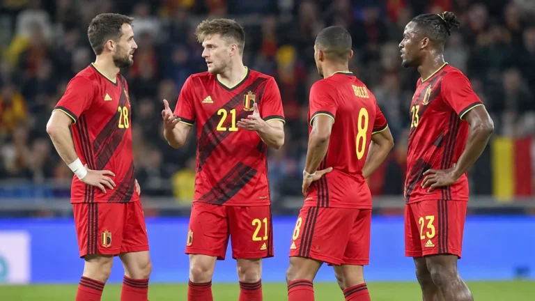 Vier Belgische spelers in rode nationale ploegtenues tijdens een wedstrijdonderbreking.