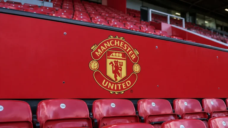 Manchester United-embleem op een rood paneel voor stadionzitjes.