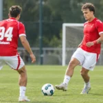 Twee voetballers in rode wedstrijdshirts tijdens een trainingsmoment.