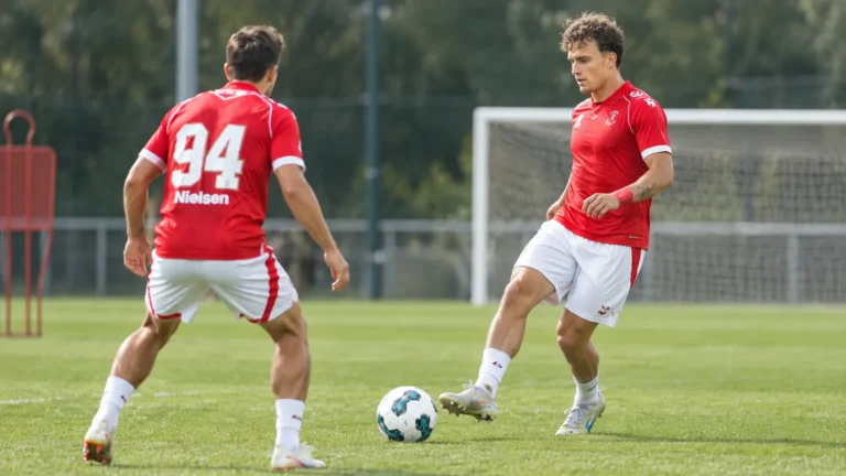 Twee voetballers in rode wedstrijdshirts tijdens een trainingsmoment.