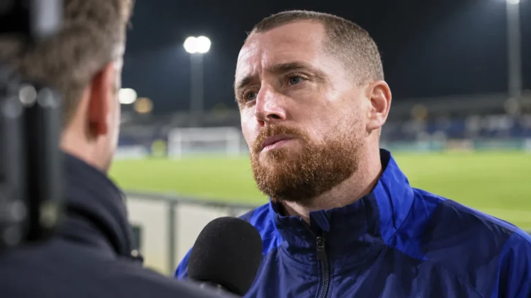 Gill Swerts tijdens een interviewmoment aan een voetbalveld.