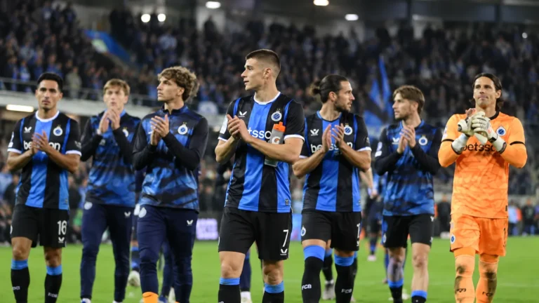 Een groep spelers van Club Brugge applaudisseert op het veld in blauw-zwarte wedstrijdkleding.