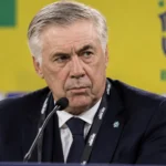 Carlo Ancelotti tijdens een persmoment in een donkere outfit.