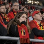 Belgische supporters in rode sjaals reageren teleurgesteld in de tribunes na een interland.