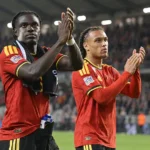 Twee spelers in rode nationale teamtenues applaudisseren na afloop op het veld.