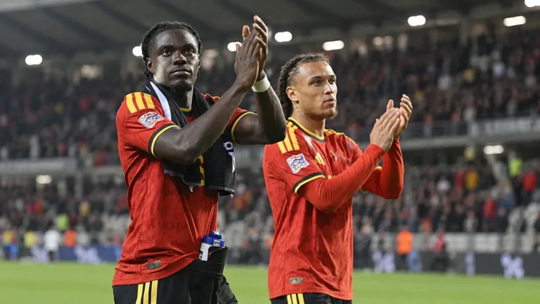 Twee spelers in rode nationale teamtenues applaudisseren na afloop op het veld.