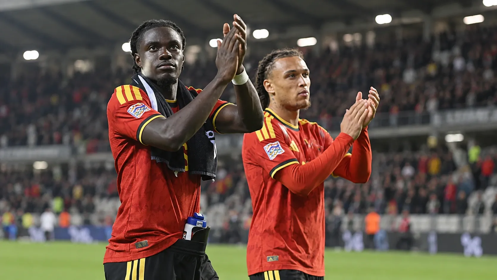 Twee spelers in rode nationale teamtenues applaudisseren na afloop op het veld.