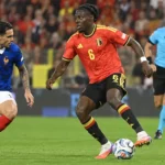 Roméo Lavia in het rode tenue van België tijdens een duel op het middenveld.
