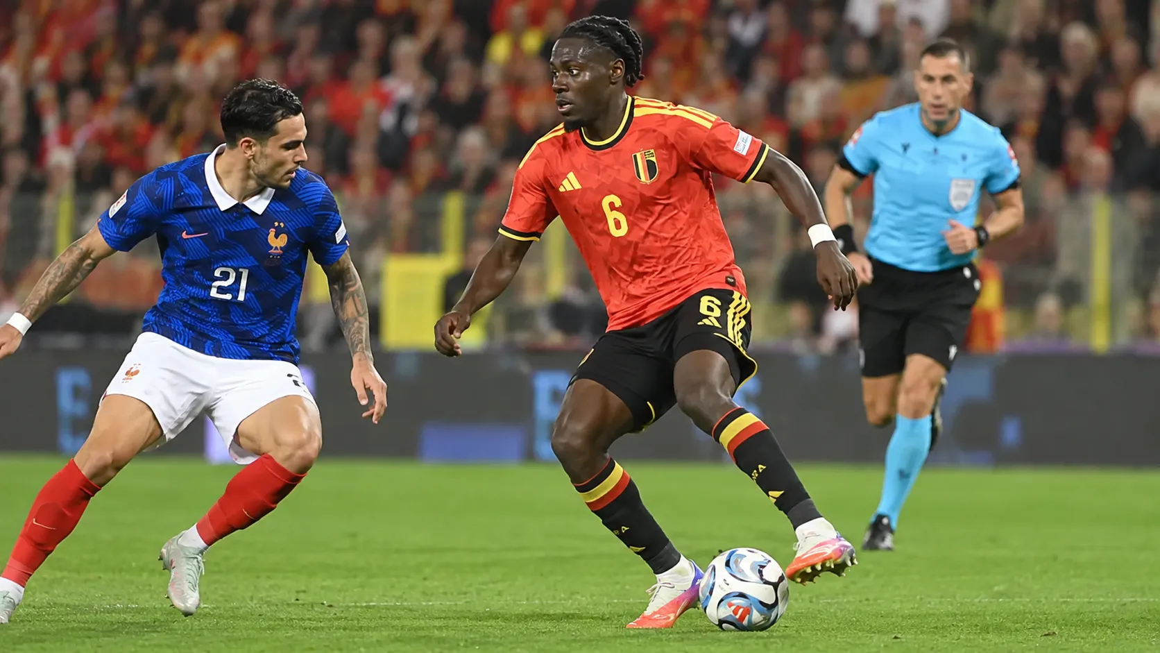 Roméo Lavia in het rode tenue van België tijdens een duel op het middenveld.