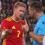 Kevin De Bruyne bespreekt een beslissing met de scheidsrechter aan de zijlijn.