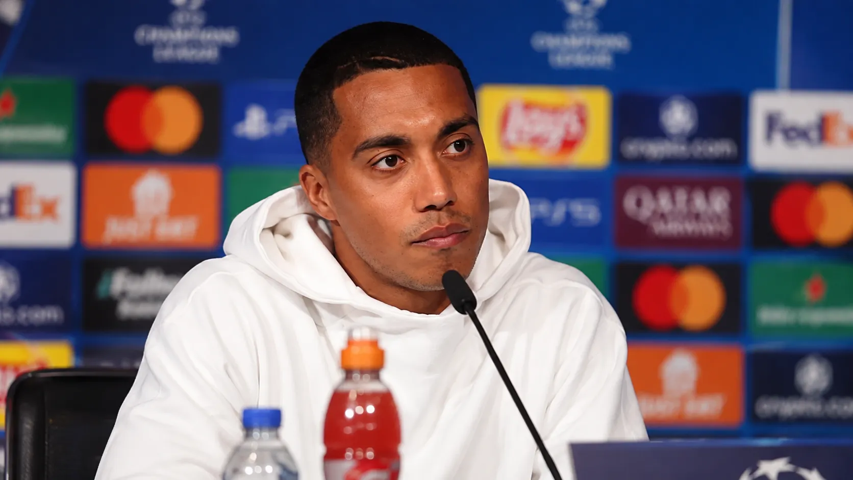 Youri Tielemans in een wit trainingsjack tijdens een mediamoment na de wedstrijd.