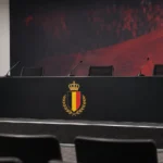 Leeg podium in een Belgische persruimte na een interland, met het embleem van de Rode Duivels op de voorkant.