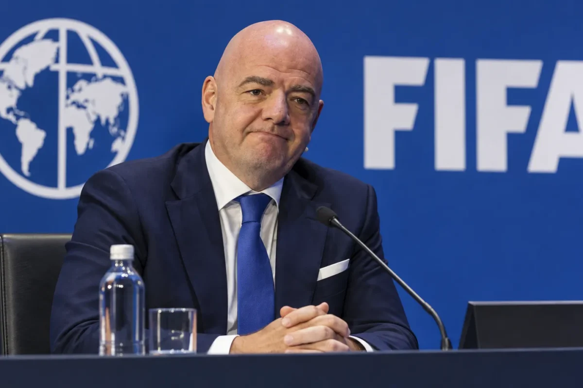 Een niet-spelende official in donker pak tijdens een FIFA-conferentie.