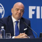 Een niet-spelende official in donker pak tijdens een FIFA-conferentie.