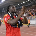 Roméo Lavia applaudisseert in een rood België-tenue langs de atletiekpiste van een stadion.