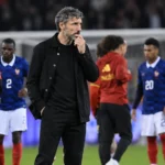 Mark van Bommel volgt de wedstrijd vanaf de zijlijn, met spelers op de achtergrond.