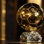 De Ballon d'Or-trofee op een kristallen sokkel in een donker verlichte ruimte.
