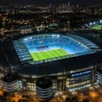 Luchtbeeld van het verlichte Etihad Stadium bij nacht.