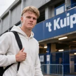 Arthur Piedfort in neutrale sportkleding bij het stadionbord van ’t Kuipje.