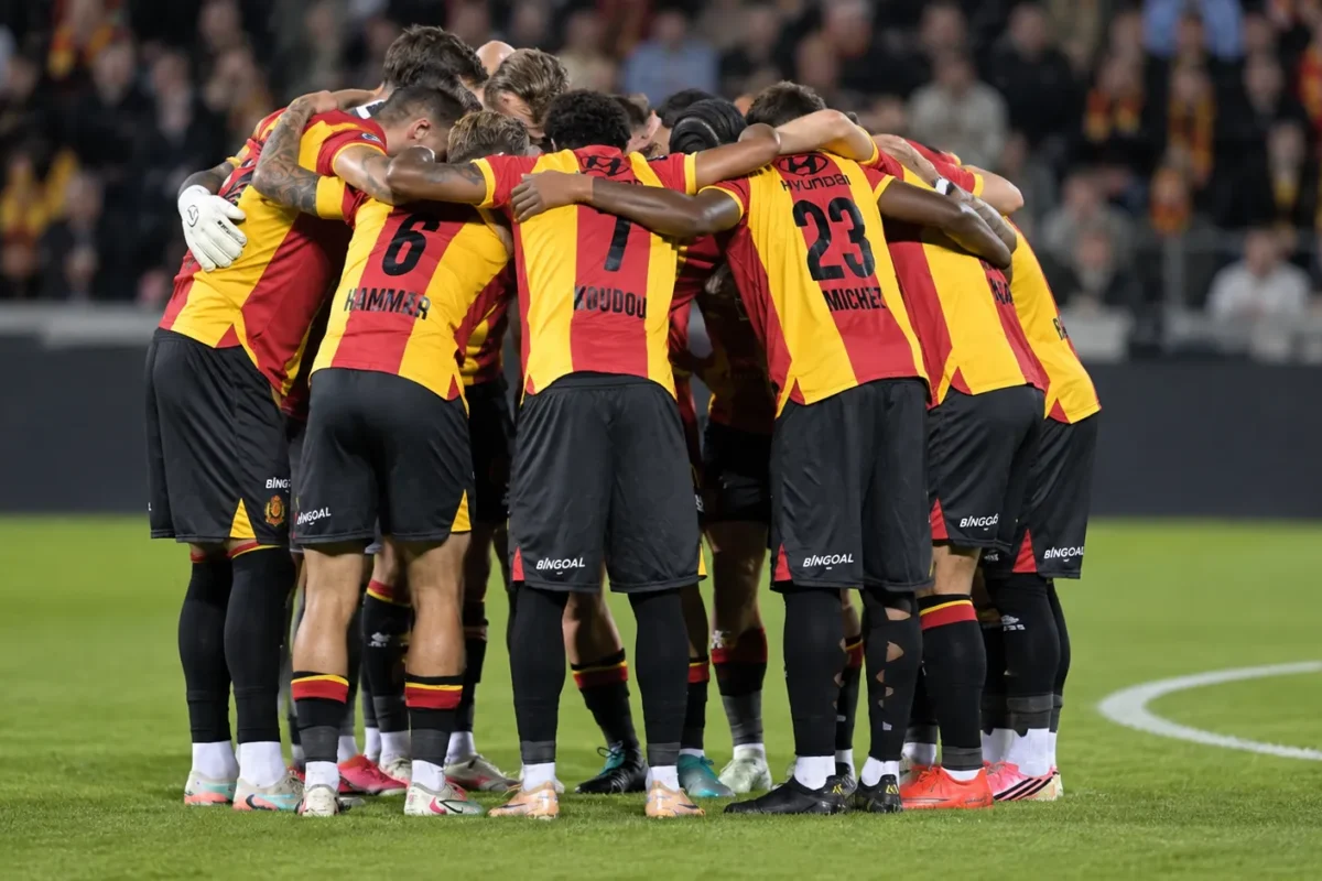 Een groep spelers vormt vlak voor de aftrap een hechte kring op het veld.